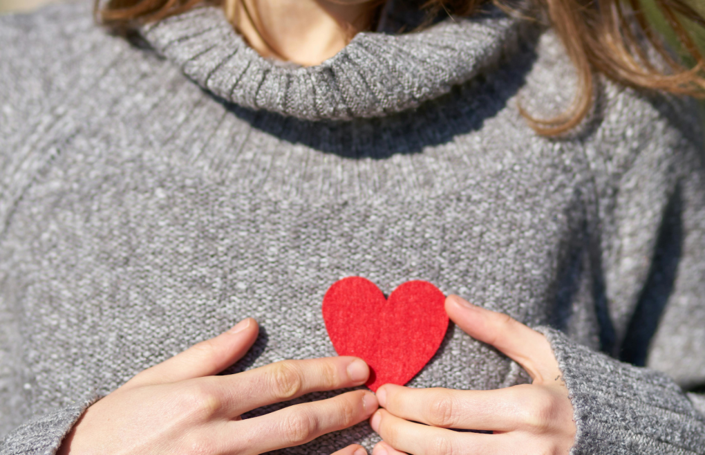 Imagen de una persona con un corazón rojo de cartulina sobre prenda gris