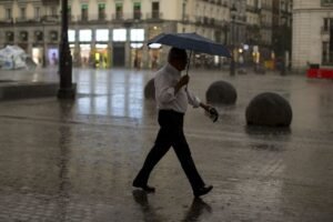 Hombre con paraguas por la calle de Madrid