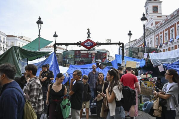 Varias personas salen de la estación de metro en la Puerta del Sol que continua rodeada de tiendas de campaña