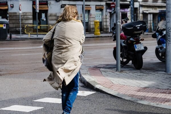 Una mujer cruza una calle de Madrid con viento
